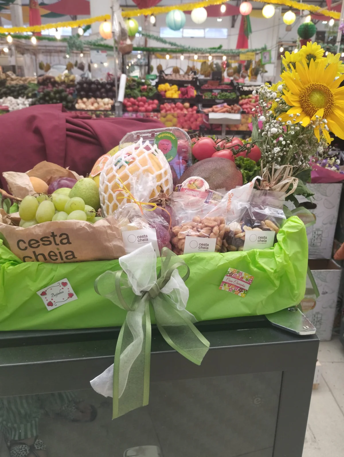 Cesta de fruta da Cesta Cheia com laço verde e flores no Mercado Manuel Firmino
